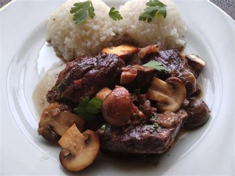 Čerstvé šampiňóny a plátky diviačieho mäsa pripravené na panvici