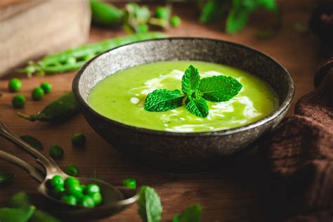 Hrášková polievka ozdobená lístkami mäty a krutónmi